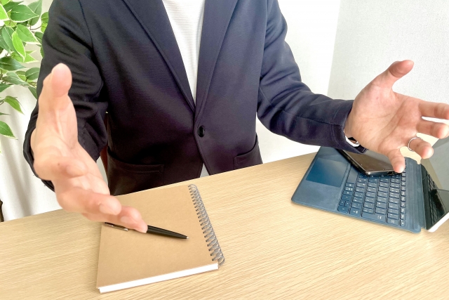 両手を広げて話すビジネスマン